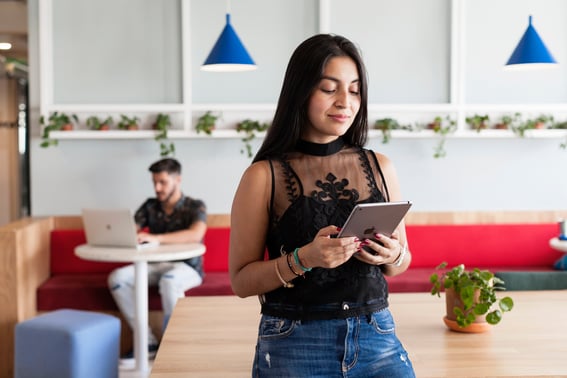 Fotografía de dos personas en una oficina con un ipad y un portátil